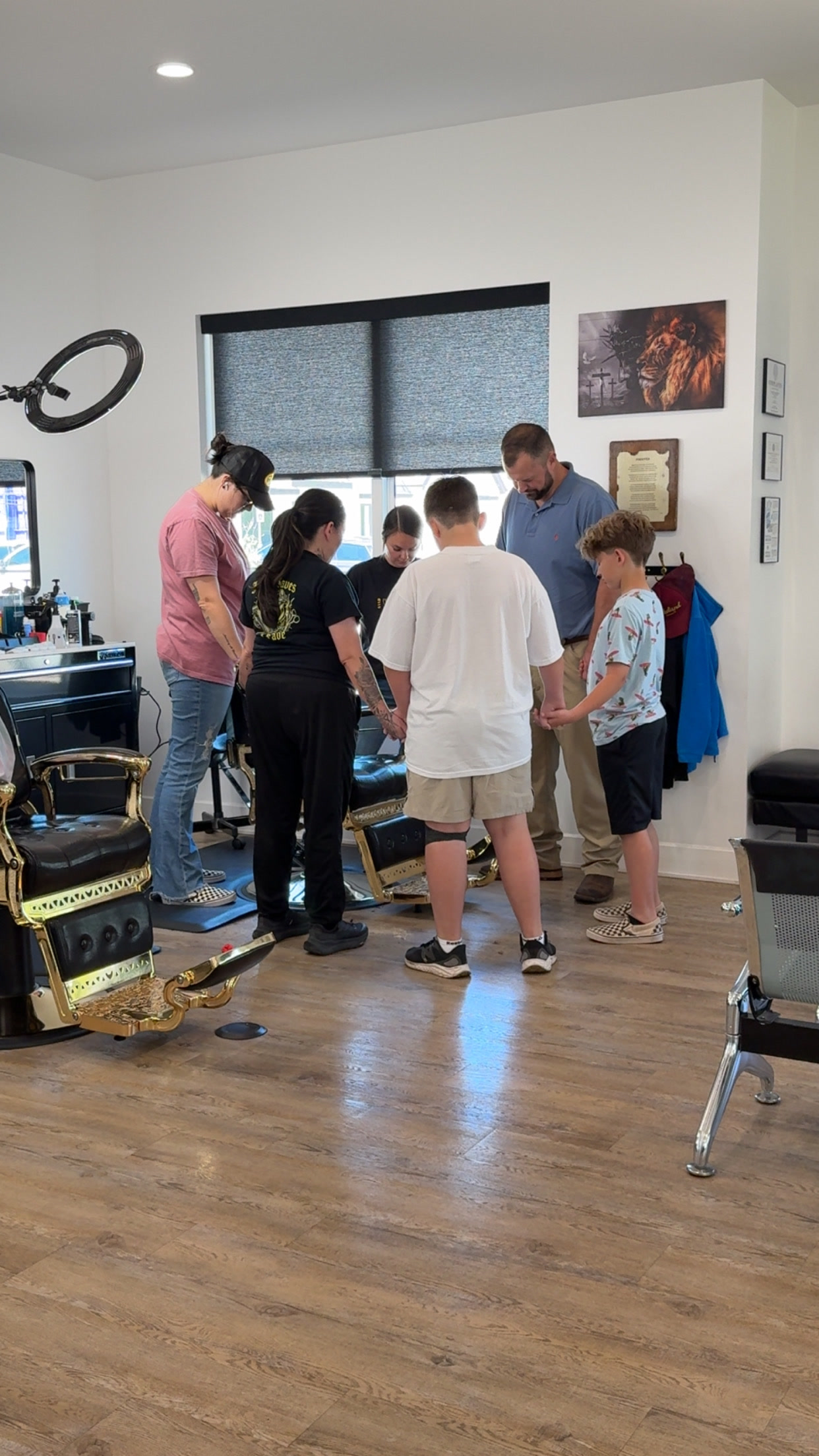 Adults and children gathered in prayer inside Crown of Thorns Barbershop
